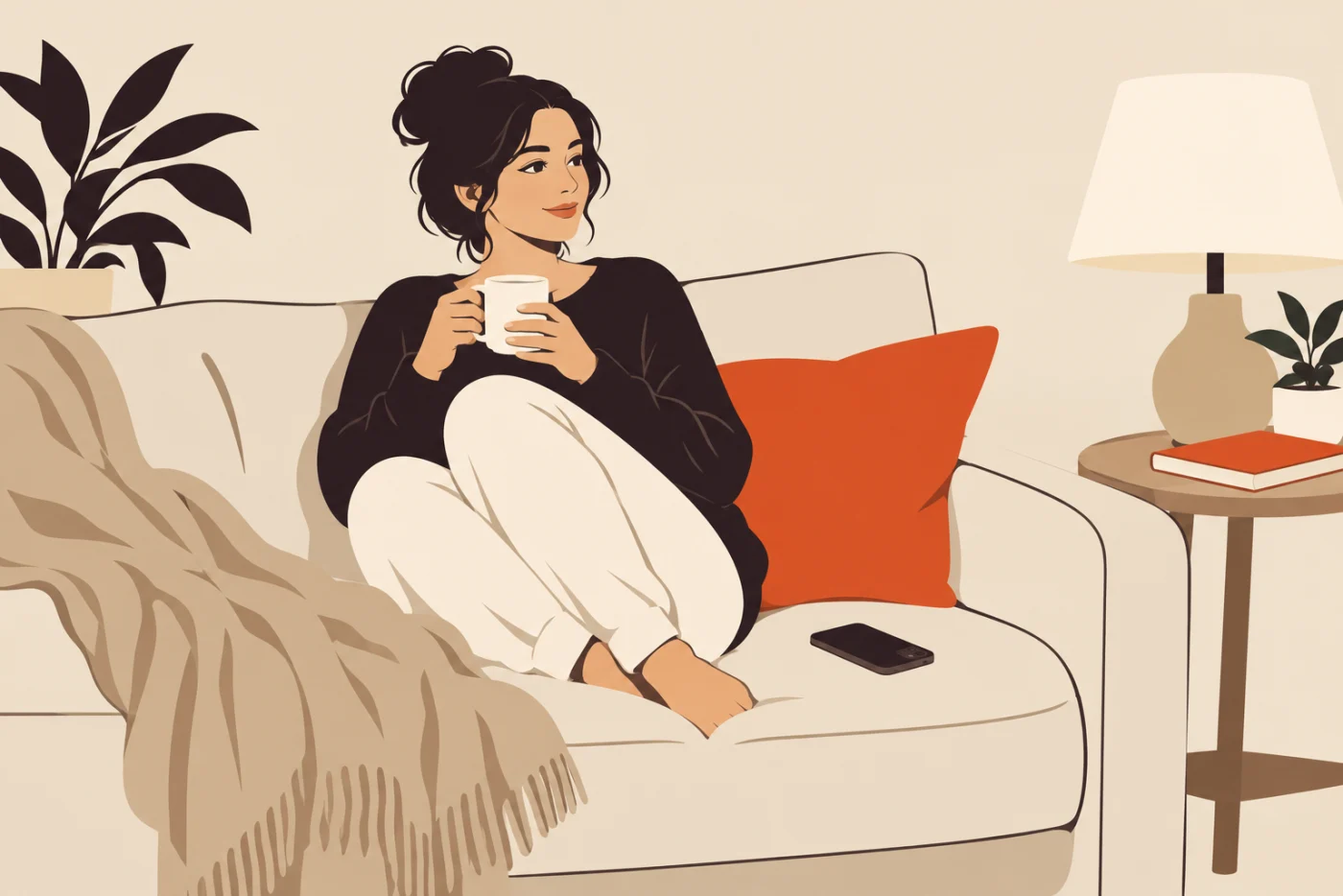 A woman relaxed on a sofa with her feet tucked up and a mug in both hands, her phone lying face down on the cushion beside her